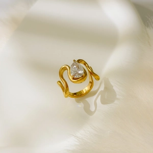 Détail de bague dorée torsadée avec zircon violet en goutte sur fond de fourrure blanche