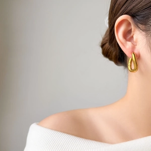 Close-up of a woman wearing gold geometric U-shaped hollow earrings in polished titanium steel