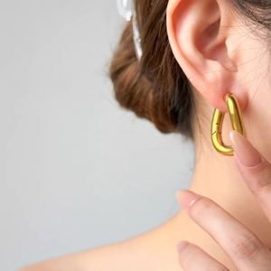 Close-up of chunky gold geometric triangular hoop earrings with polished mirror finish