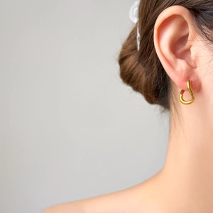 Minimalist gold U-shaped hollow geometric earrings with organic curves worn by a model