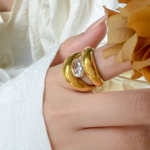 Detail of 18K gold plated wide ring with large round zircon on a person's hand