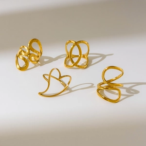 Macro view of four minimalist 18K gold-plated rings with abstract hollow heart designs