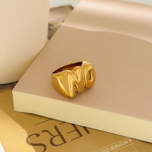 Macro detail of chunky gold ring with NO letter design and hollow star carving
