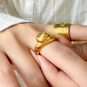 Detail of 18K gold-plated titanium steel rings with spiral shell and grooved star design