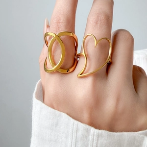 Detail of hollow heart and layered geometric rings in 18K gold plated titanium