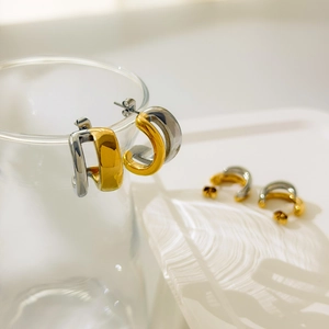 Gros plan de boucles d'oreilles bicolores en forme de C en or et argent suspendues au verre
