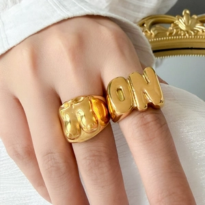 Macro shot of 18K gold plated 'ON' letter and female torso art sculpture rings
