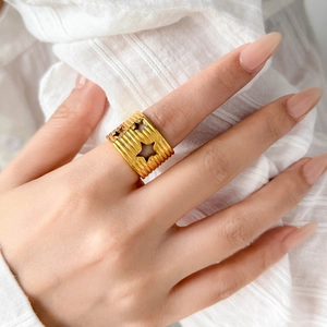 Detailed view of wide gold-plated ring with U-groove texture and hollow star cutouts
