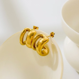 Détail de larges boucles d'oreilles dorées en C avec texture rainurée sur une tasse