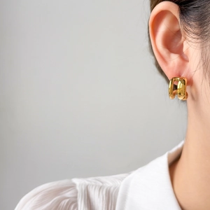 Gros plan de boucles d'oreilles créoles en forme de C bicolores en acier plaqué or 18 carats