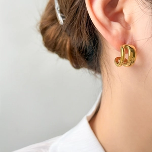 Détail de boucles d'oreilles en C plaquées or 18 carats portées par un mannequin