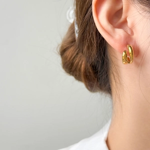 Gros plan de boucles d'oreilles créoles en C bicolores en acier titane plaqué or 18 carats
