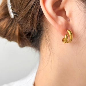 Gros plan de boucles d'oreilles minimalistes dorées bicolores en C portées sur l'oreille