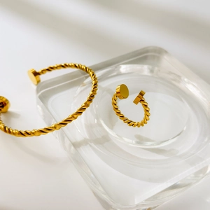 Detail of gold twisted cable cuff bracelet and matching ring set on acrylic display