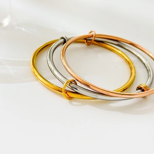 Detail of three-tone stackable bangles in gold, silver, and rose gold polished finish