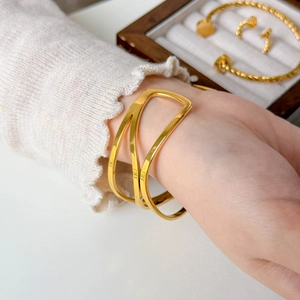 Detail of a minimalist gold cutout cuff bracelet with multilayered sleek geometric lines