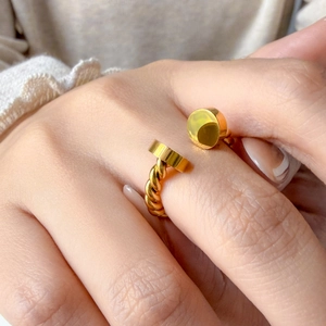 Close-up of golden open ring with twisted band design worn on finger for jewelry detail