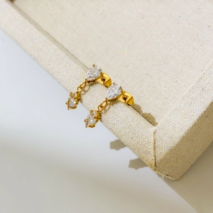 Macro shot of 18K gold plated drop earrings with clear marquise zirconia on linen