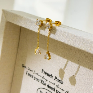 Detailed view of pear-cut zircon drop earrings with 18K gold-plated chains on jewelry box