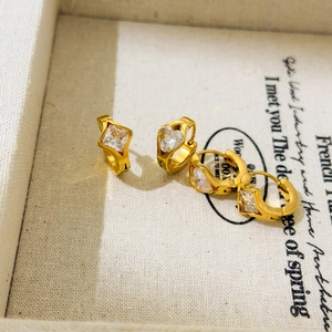 Macro view of gold plated earrings featuring square and heart-shaped zircon stones