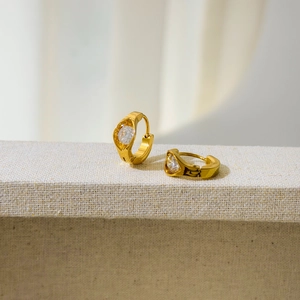 Detail of round white zircon stones set in 18K gold-plated stainless steel hoop earrings