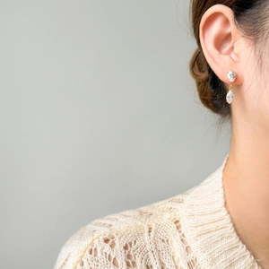 Detail of gold-plated drop earrings with marquise and teardrop cubic zirconia on a model