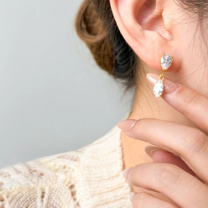 18K gold plated drop earrings with sparkling pear-cut zircon stones worn by a model