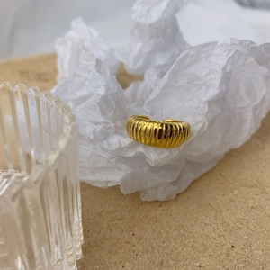 Macro shot of gold croissant ring featuring textured vertical stripes and adjustable open band