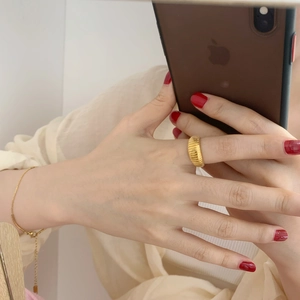Detail of a gold croissant style textured ring with minimalist gold chain bracelet