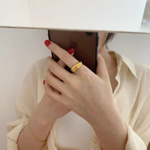 Detail of a gold-toned croissant ring featuring a textured threaded design on finger
