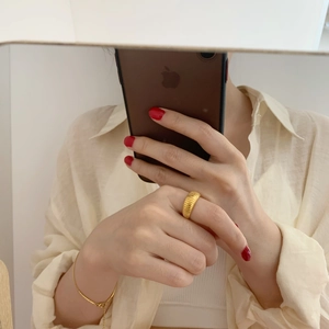 Detail of a thick golden textured ring featuring a stylish ribbed wave pattern on finger