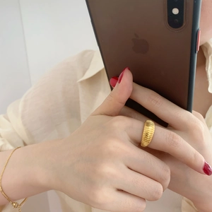 Macro detail of wide golden textured ring and minimalist chain bracelet set