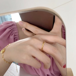Close-up of minimalist gold olive leaf ring and heart charm bracelet set on hand