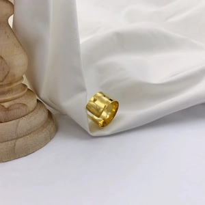 Detail of wide hammered texture gold ring set on white fabric with vintage backdrop