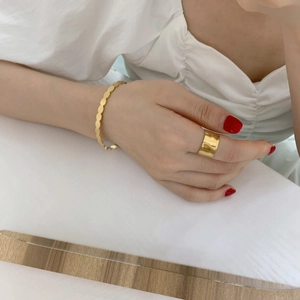 Detail of wide textured gold index ring and round disk bracelet on model hand