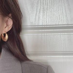 Close-up of a model wearing chunky gold U-shaped geometric earrings in a minimalist style