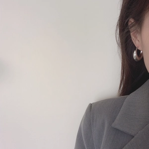 Close-up of minimalist silver hoop earring with thick polished finish on model's ear