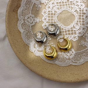 Elegant gold and silver U-shaped crescent hoop earrings displayed on lace fabric