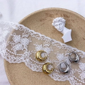 Macro view of thick C-shaped metal hoop earrings in gold and silver on a decorative tray