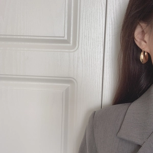 Close-up of elegant gold teardrop earrings worn by a model in a minimal fashion setting