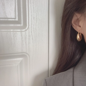 Close-up of elegant gold teardrop earrings worn by a model in a modern style