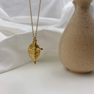 Vue détaillée de la médaille de la Vierge Marie dorée et du pendentif croix sur tissu