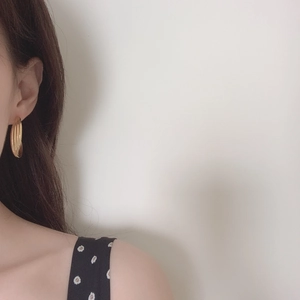 Elegant gold multi-layered ribbed hoop earrings worn by a model in a side profile view