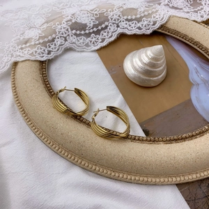 Close-up of golden multi-layered spiral hoop earrings on vintage frame with lace