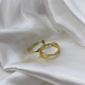 Elegant gold multi-layered spiral hoop earrings on a white satin fabric background