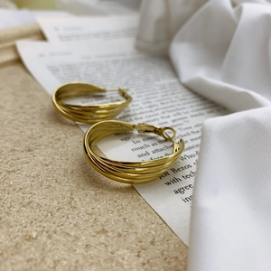 Detailed close-up of gold multi-layered circular hoop earrings on vintage paper texture