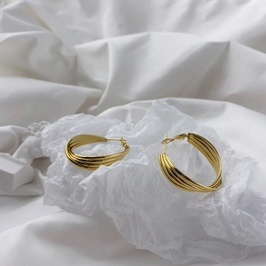 Close-up of golden multi-layer hoop earrings with layered metallic circles on white paper