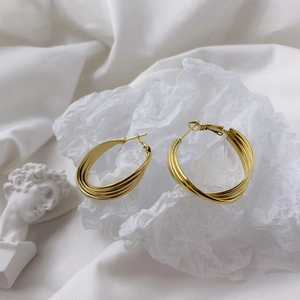 Detail of gold multi-layered circular hoop earrings on artistic white textured display