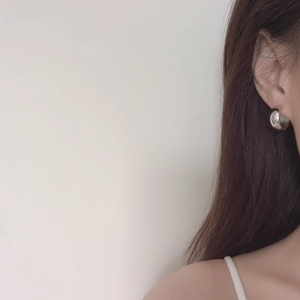 Close-up of thick silver irregular round geometric earrings with high-shine polished finish