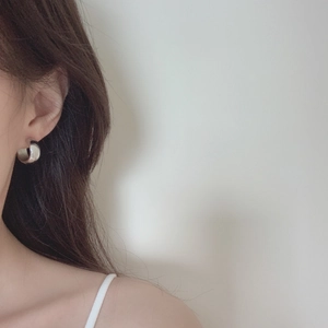 French minimalist irregular geometric silver hoop earring worn by a model
